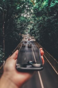 forced perspective photography of cars running on road below smartphone